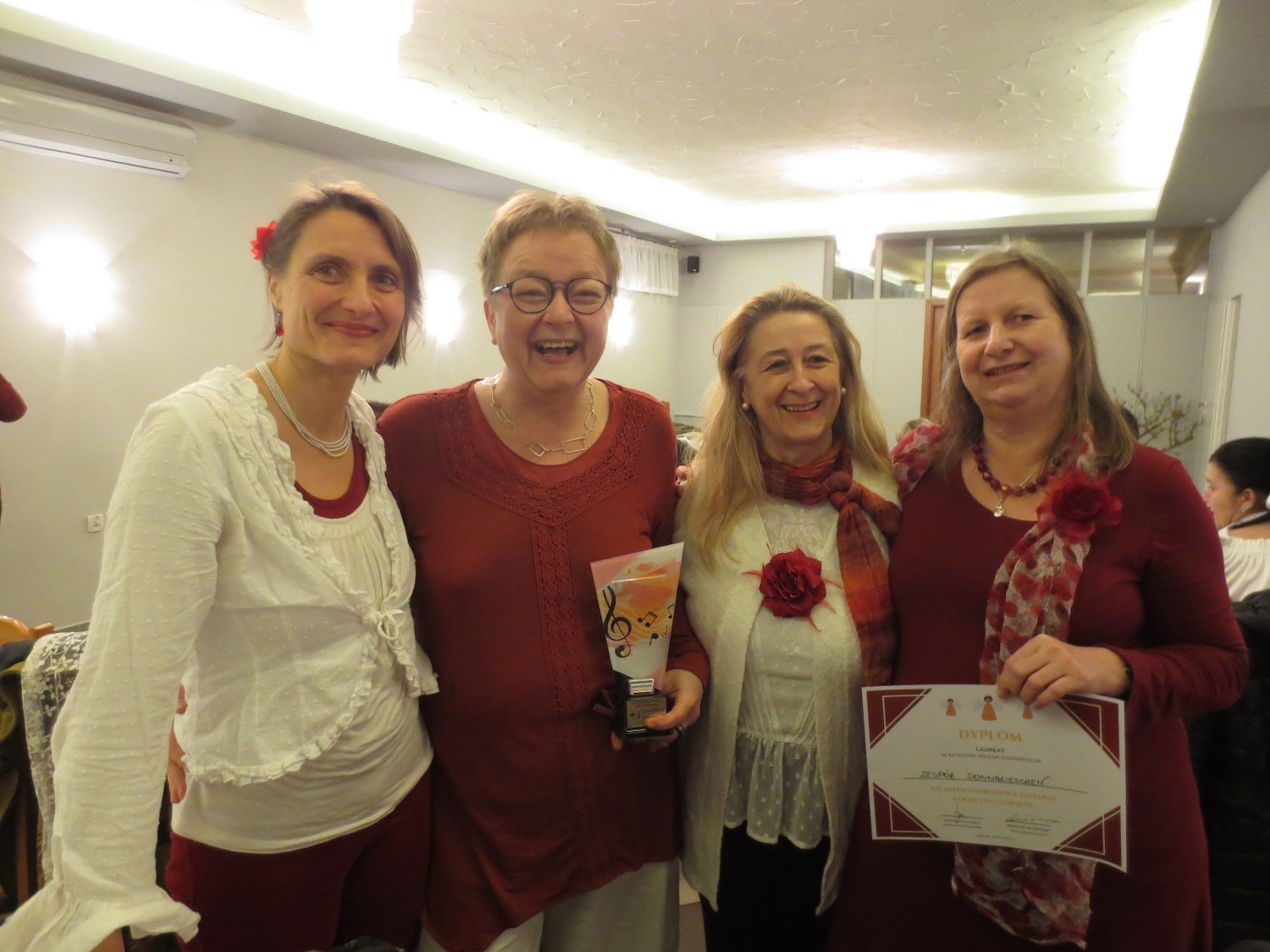 Vokal-Ensemble DonnaLiedchen, drei lachende Frauen in rot-weißer Kleidung mit ihrem Pokal